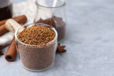 Granüle edilmiş hazır kahve ölçü kabı ve baharatlar gri desenli masa üzerinde, yakın plan. Metin için boşluk