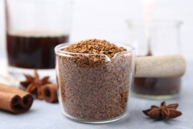 Granüle edilmiş hazır kahve ölçü kabı ve baharatlar gri masa üzerinde hafif arka plan, yakın çekim