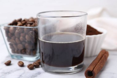 Kahve fincanda tazeleniyor, tarçın çubuğu ve fasulye beyaz mermer masada, yakın plan.