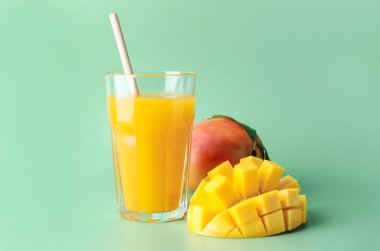 Bardakta lezzetli mango suyu ve yeşil arka planda taze meyve.