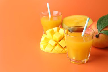 Bardakta lezzetli mango suyu ve turuncu arka planda taze meyve, yakın plan. Metin için boşluk