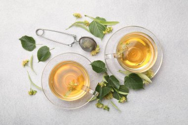 Taze ıhlamur çayı fincanda ve çiçekler açık gri masada, düz yerde.