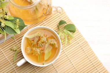 Taze ıhlamur çayı, çaydanlık ve çiçekler beyaz ahşap masada, düz yerde. Metin için boşluk