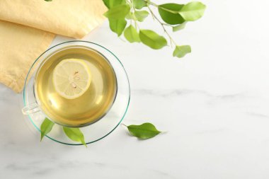 Limonlu yeşil çay ve beyaz mermer masa üzerindeki yapraklar düzleşir. Metin için boşluk