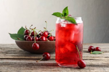 Buzlu vişneli gazoz, böğürtlen ve nane şekeri ahşap masada, yakın plan.