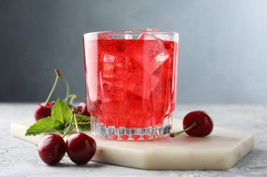 Buzlu vişneli gazoz, böğürtlen ve bardakta nane şekeri. Gri desenli masa, yakın plan.