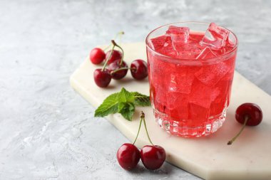 Buzlu vişneli gazoz, böğürtlen ve bardakta nane şekeri. Gri desenli masa, yakın plan. Metin için boşluk