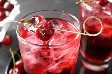 Buzlu vişneli gazoz ve bardaklar gri masada, yakın plan.
