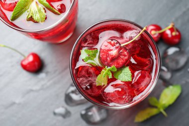 Buzlu vişneli gazoz, böğürtlen ve nane şekeri gri masada, düz yerde.