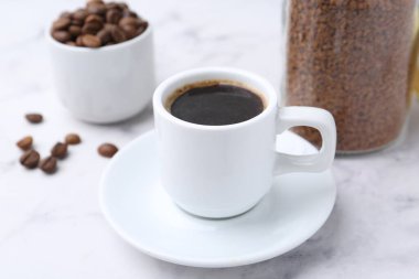 Aromatik sıcak içecek, hazır kahve ve fasulye beyaz mermer masada, yakın plan.