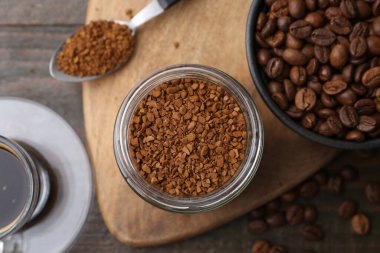 Cam kavanozdaki anlık kahve, sıcak içecek ve fasulye ahşap masada, düz uzanmış.