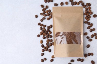 Hafif arka planda hazır kahve ve fasulye torbası, düz uzanmış. Metin için boşluk