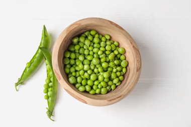 Taze taze bezelyeler beyaz ahşap masada, üst manzara