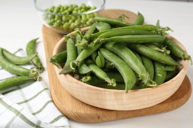 Taze taze bezelyeler beyaz ahşap masada, yakın plan.