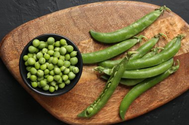 Taze taze bezelyeler siyah masada, üst tarafta.
