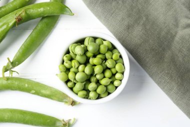 Taze taze bezelyeler beyaz ahşap masada, düz yatıyordu.