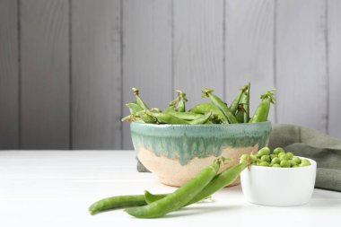 Taze taze bezelyeler beyaz ahşap masada, yakın plan. Metin için boşluk