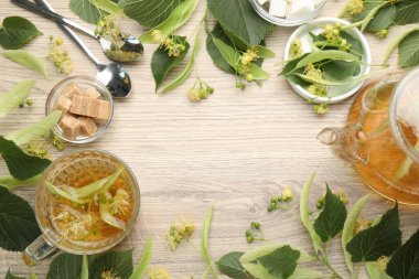 Fincandaki taze ıhlamur çayından yapılmış çerçeve, çaydanlık, şeker küpleri ve tahta masadaki çiçekler, düz yatak. Metin için boşluk