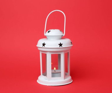 Kırmızı arka planda yanan mum ile güzel beyaz dekoratif fener