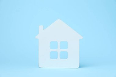 Açık mavi arka planda bir beyaz ev modeli