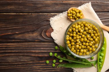 Kavanozda bezelye turşusu ve ahşap masada kabuklar, düz yatış. Metin için boşluk