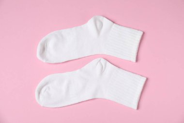 Pembe arka planda bir çift rahat beyaz çorap, üst manzara