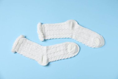 Açık mavi arka planda bir çift rahat beyaz çorap, üst manzara