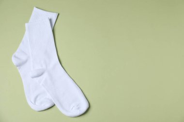 Açık yeşil arka planda bir çift rahat beyaz çorap, üst manzara. Metin için boşluk
