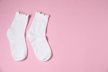 Pembe arka planda bir çift rahat beyaz çorap, üst manzara. Metin için boşluk