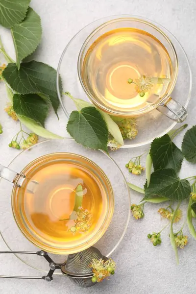 Taze ıhlamur çayı fincanda ve çiçekler açık gri masada, düz yerde.