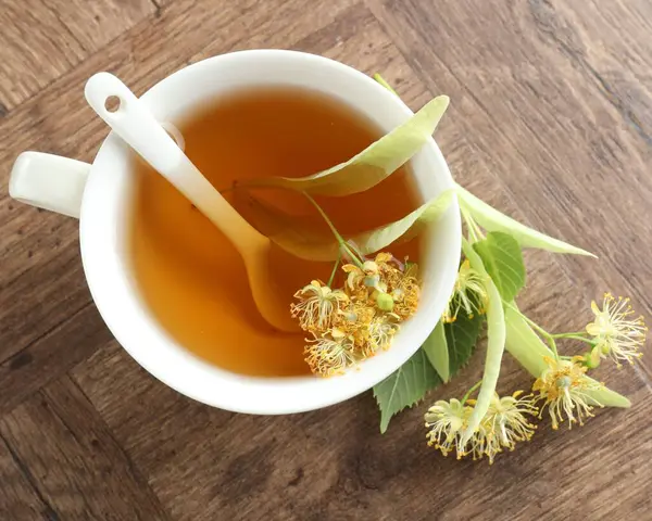 Fincanda nefis ıhlamur çayı, ahşap masada yapraklar ve çiçekler, düz uzanmış