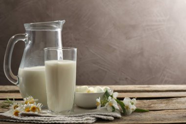 Taze süt, mozzarella topları ve ahşap masada çiçekler, yazı için yer. Süt ürünleri