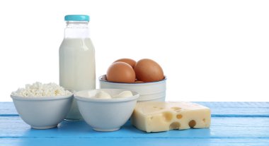 Farklı süt ürünleri ve yumurtalar mavi ahşap masada beyaz arka planda