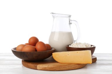 Farklı süt ürünleri ve yumurtalar beyaz arka plana karşı ahşap masa üzerinde