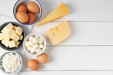 Farklı süt ürünleri ve yumurtalar beyaz ahşap masada, düz yerde. Metin için boşluk