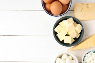 Farklı süt ürünleri ve yumurtalar beyaz ahşap masada, düz yerde. Metin için boşluk