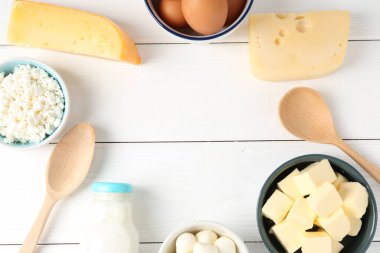 Beyaz ahşap masa üzerinde farklı süt ürünleri ve yumurtalardan oluşan bir çerçeve. Metin için boşluk