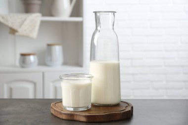 Süt ürünleri. Bardaktaki taze süt ve içerideki gri dokulu masada duran şişe.