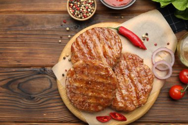 Lezzetli hamburger köfteleri, domatesler, ahşap masa üzerindeki baharatlar, düz yatak. Metin için boşluk