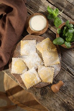 Ahşap masada pişmemiş mantı ve fesleğen.