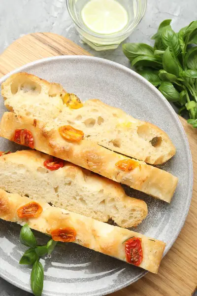 Domatesli, fesleğenli ve bardaklı lezzetli Focaccia parçaları gri desenli masa üzerinde, düz yatıyordu.
