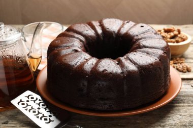 Lezzetli çikolatalı kek, sunucu, ceviz ve çay ahşap masada, yakın plan.