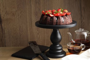 Çilekli çikolatalı kek ve ahşap masada çay.