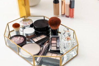 Farklı makyaj ürünleri olan tepsi beyaz masada, yakın plan