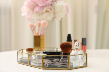 Beyaz masadaki farklı makyaj ürünlerinin olduğu tepsi kapalı, yakın çekim