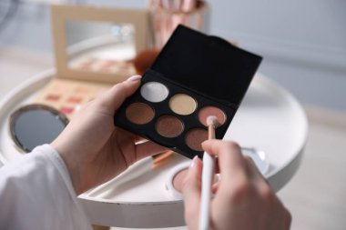 Kapalı bir masada fırça ve göz falı bir kadın, yakın plan.