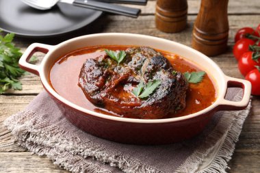 Biftek ve soslu geleneksel ossobuko tabağı ahşap masada servis edilir.