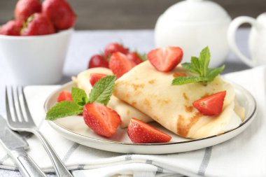 Kremalı, çilekli ve naneli krepler masada, yakın plan.