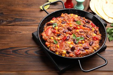 Pişirme kabında lezzetli biberli makarna ve ahşap masada yassı ekmek, yakın plan. Metin için boşluk