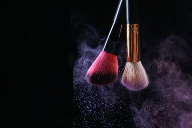 Siyah arka planda renkli göz gölgeli makyaj fırçaları, yakın plan. Metin için boşluk